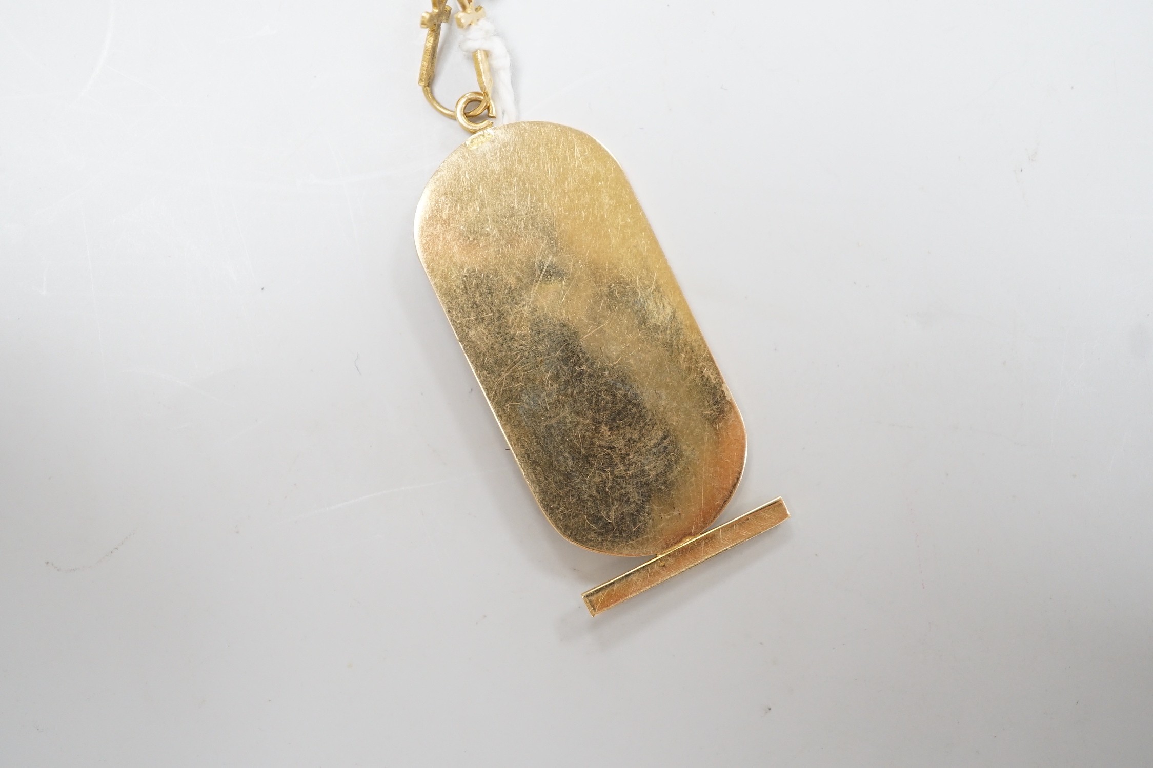 An Egyptian yellow metal pendant, overall 57mm, on a 750 chain, 57cm, gross weight 12.4 grams.